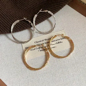 Primo piano di orecchini a cerchio a doppio strato in oro e argento su tessuto.