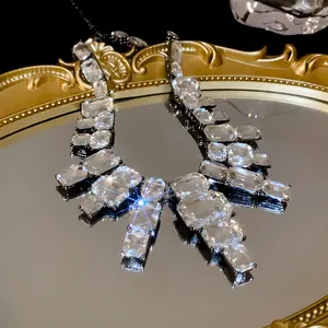 Close-up of glamorous square crystal statement necklace on gold mirror tray reflection