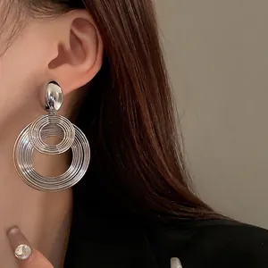Orecchini tondi in metallo intrecciato oversize con finitura argento minimalista.