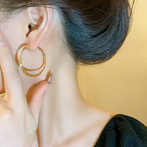 Primo piano di eleganti orecchini a cerchio intrecciati dorati su una modella