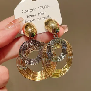 Dettaglio di orecchini ad anelli concentrici metallici oro e argento su cartoncino