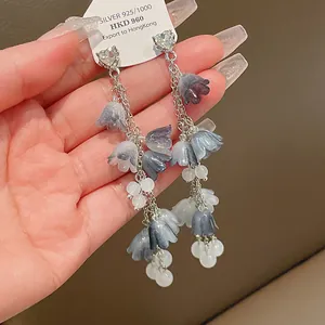Gros plan détaillé de boucles d'oreilles à pompons muguet avec clous en cœur cristal