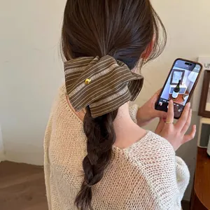 Detailed view of a retro brown striped oversized scrunchie with a gold heart on a braid