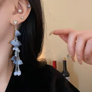 Vue macro d'élégantes boucles d'oreilles fleur à pompons en argent et pétales bleus