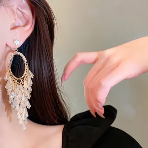 Elegant gold oval rhinestone earrings with sparkling crystal tassels on a model