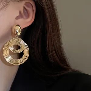 Dettaglio ravvicinato di grandi orecchini circolari in filo metallico dorato a spirale
