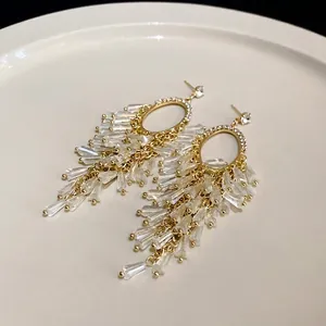 Elegant gold-plated oval earrings featuring sparkling crystal tassels and silver needles.