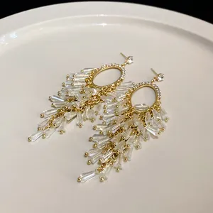 Close-up of elegant gold oval stud earrings with sparkling crystal bead tassels
