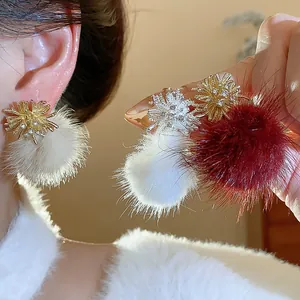 Detail view of sparkly fireworks earrings with soft white and burgundy fur pom poms