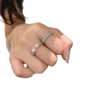 Elegante set di anelli con zirconi e perle intrecciate indossati su una mano femminile