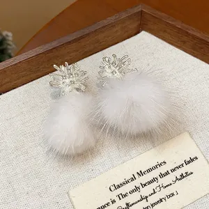 Close-up view of elegant snowflake stud earrings featuring fluffy white faux fur pom-poms