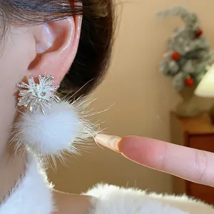 Detailed close-up of silver snowflake firework earrings with a soft white fur ball