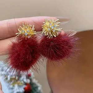 Detail view of firework-style earrings with burgundy faux fur pom-poms