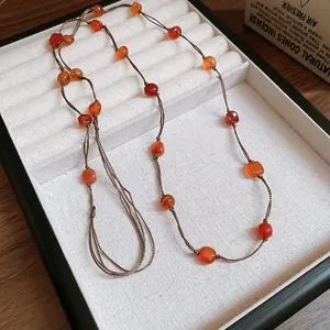 Close-up detail of a vintage ethnic colorful glass bead necklace in a white display box