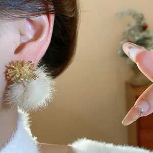 Macro detail of gold firework stud earrings featuring white fur ball and sparkling crystals.
