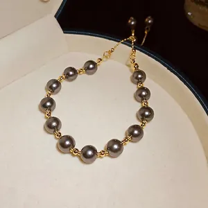 Bracciale regolabile vintage con perle grigie e perline dorate in una scatola regalo