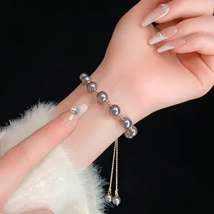 Bracciale regolabile con perle grigie e perle dorate sul polso di una modella
