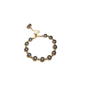 Elegante bracciale regolabile in perle grigie con perline dorate su uno sfondo bianco