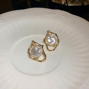 Elegant irregular gold-tone pearl stud earrings with retro design shown on white plate