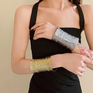Elegant wide metal open cuff bracelet set in gold and silver finish worn by a model