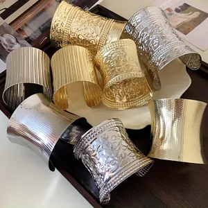 Detailed view of assorted gold and silver metal cuff bracelets with various textures