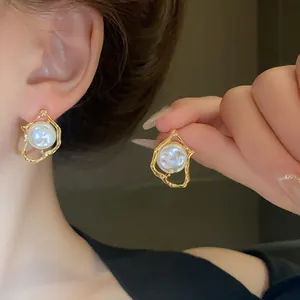 Detailed close-up showing elegant irregular gold metal earrings with white pearls