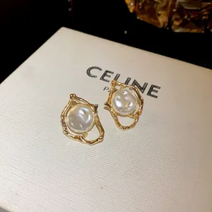 Macro detail view of irregular gold stud earrings featuring an elegant white pearl center.