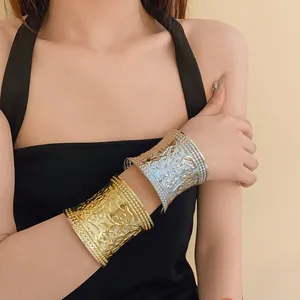 Close-up of gold and silver metal cuff bracelets with embossed texture on model's arm