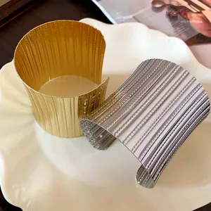 Macro detail showing textured patterns on wide gold and silver metal cuff bracelets