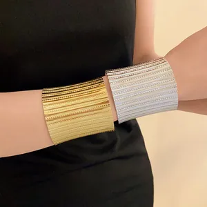 Close-up of elegant gold and silver textured metal cuff bracelets on wrist