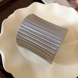 Macro view of wide silver metallic cuff bracelet with pleated texture