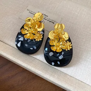 Elegant vintage oval resin stud earrings featuring detailed golden metallic flowers