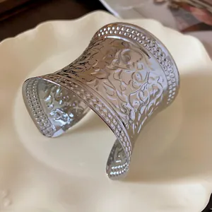 Detailed view of a silver-toned metal cuff bracelet with ornate hollow floral patterns