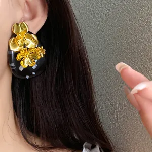 Vintage gold floral resin oval stud earrings with silver needles shown on ear
