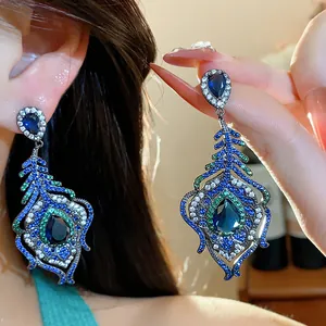 Detailed view of vintage peacock feather earrings with blue and green zircons.