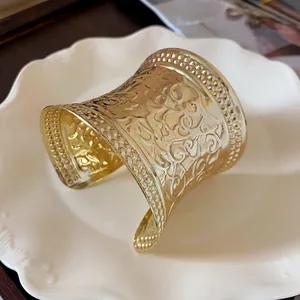 Detailed view of a vintage gold metal cuff bracelet with embossed floral patterns