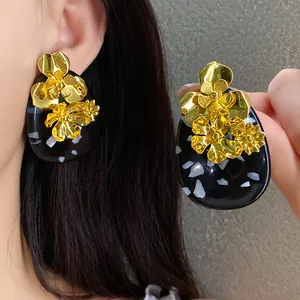 Close-up of vintage-style floral resin earrings with metallic gold flower accents