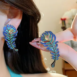 Detailed macro shot of elegant feather stud earrings with blue and green zircons