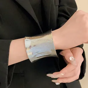 Close-up of wide silver textured cuff bracelet worn with a black blazer