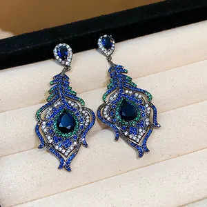 Macro detail of vintage peacock feather drop earrings featuring blue and green zircon stones