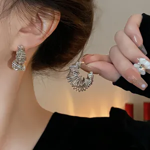 Detailed view of fashionable irregular silver wire-wrapped hoop earrings worn on model