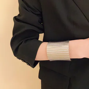 Close-up of a stylish wide silver textured metal cuff bracelet on a black blazer sleeve