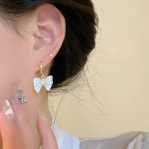 Primer plano detallado de un elegante pendiente de mariposa blanca en la oreja de la modelo
