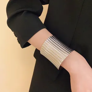Macro view of a wide silver metal cuff bracelet with vertical ribbed texture worn over a black blazer