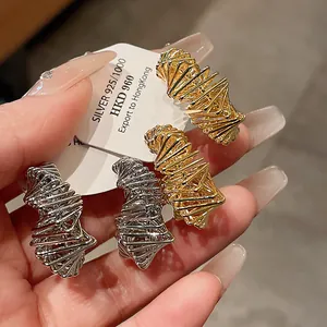 Close-up of irregular gold and silver plated geometric earrings with 925 silver tags
