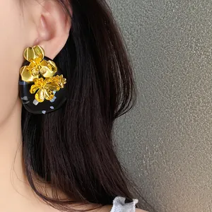 Close-up detail of vintage golden flower cluster on black resin oval earring on ear