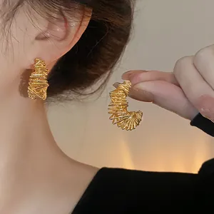 Close-up of gold-plated irregular wire-wrapped hoop earrings with textured detail.