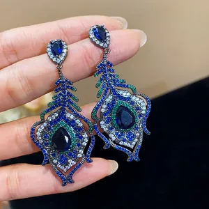 Detailed view of retro palace style feather earrings with blue and green cubic zirconia stones