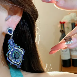 A detailed view of vintage peacock feather earrings with sparkling blue and green zircons.