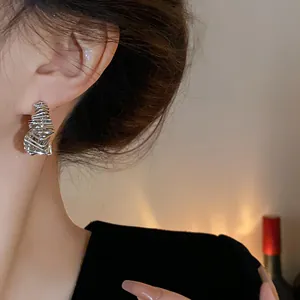 Close-up of elegant irregular silver wire earrings worn by a model in warm lighting